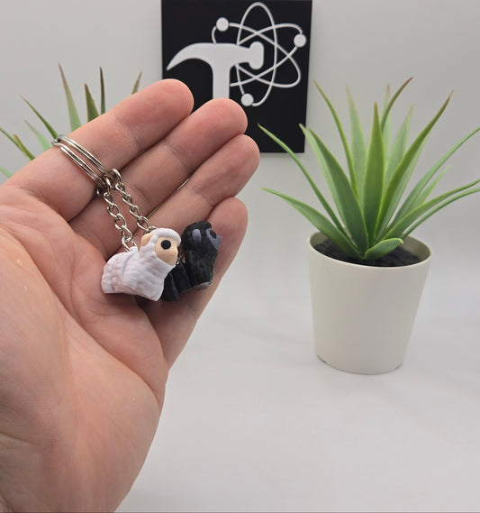 mini articulated sheep on keychains with plants and the crafticist logo in the background