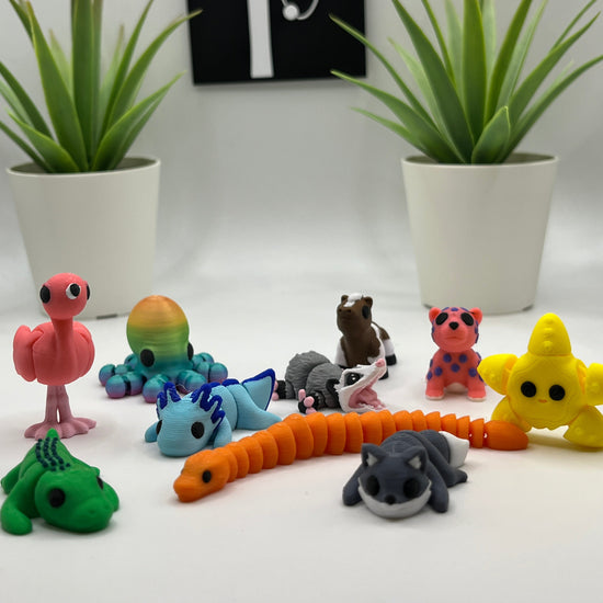 Colorful articulated animals on a white surface with plants and a black and white sign in the background.