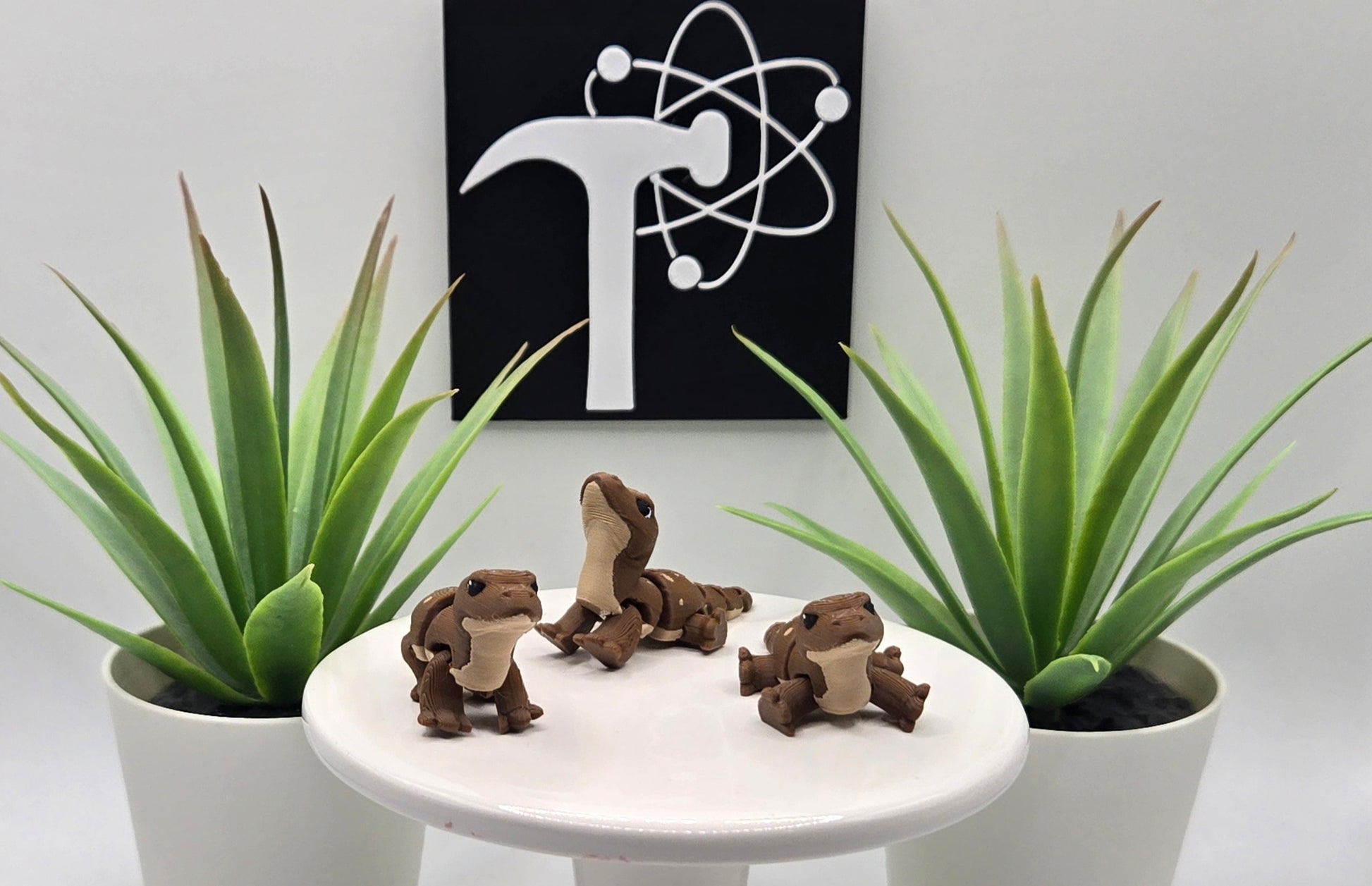 mini articulated komodo dragons on a white pedestal with plants and the Crafticist logo in the background