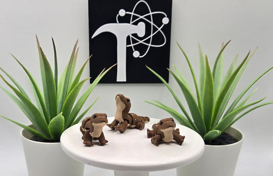 mini articulated komodo dragons on a white pedestal with plants and the Crafticist logo in the background