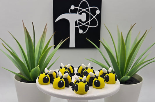 several mini articulated bees on a white pedestal with plants and the Crafticist logo in the background