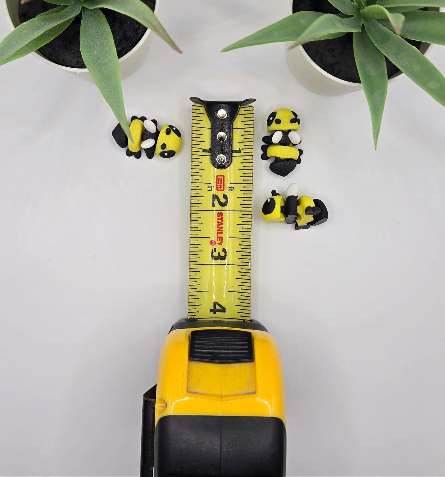 small articulated bumble bee toys with a tape measure on a white surface with plants in the background