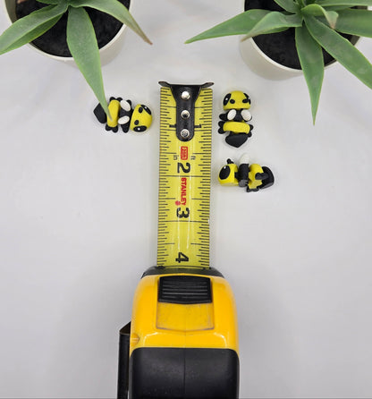 small articulated bumble bee toys with a tape measure on a white surface with plants in the background