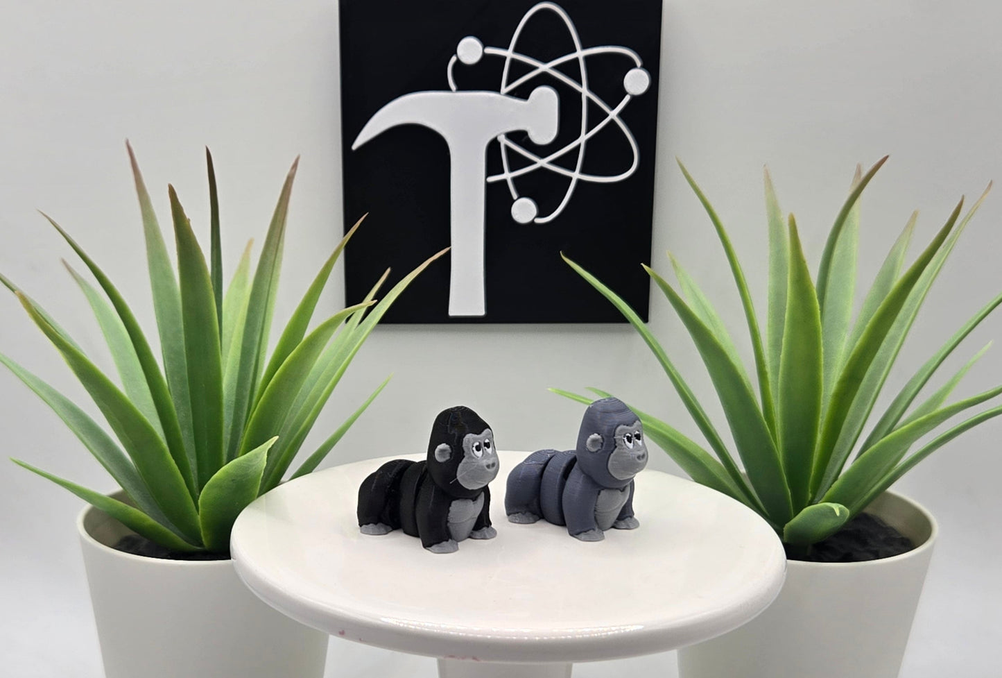 two mini articulated gorillas on a white pedestal with two plants and the crafticist logo in the background