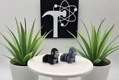 two mini articulated gorillas on a white pedestal with two plants and the crafticist logo in the background