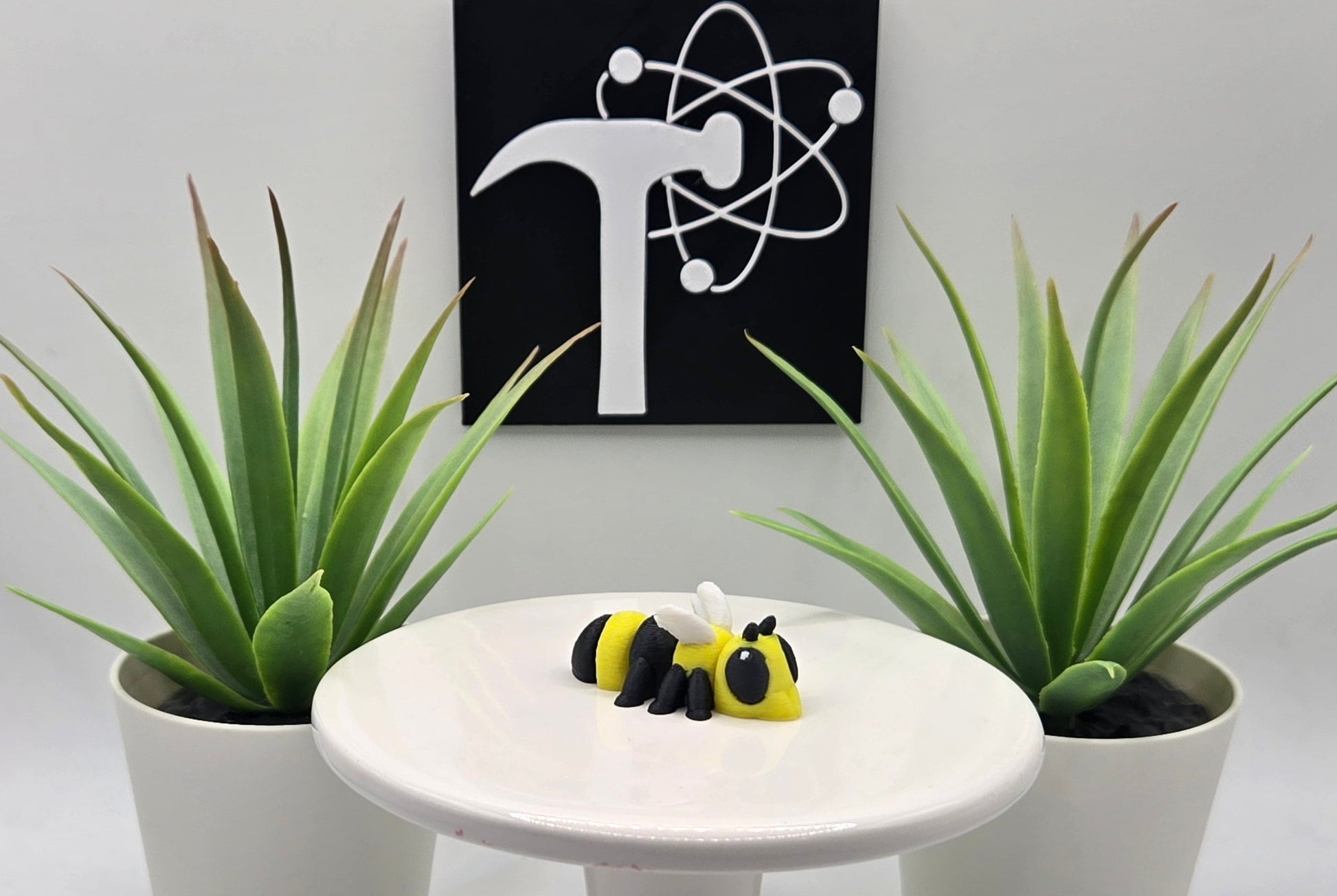 a mini articulated hornet toy sitting on a white pedestal with a white background and the crafticist logo on the wall.