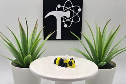 a mini articulated hornet toy sitting on a white pedestal with a white background and the crafticist logo on the wall.