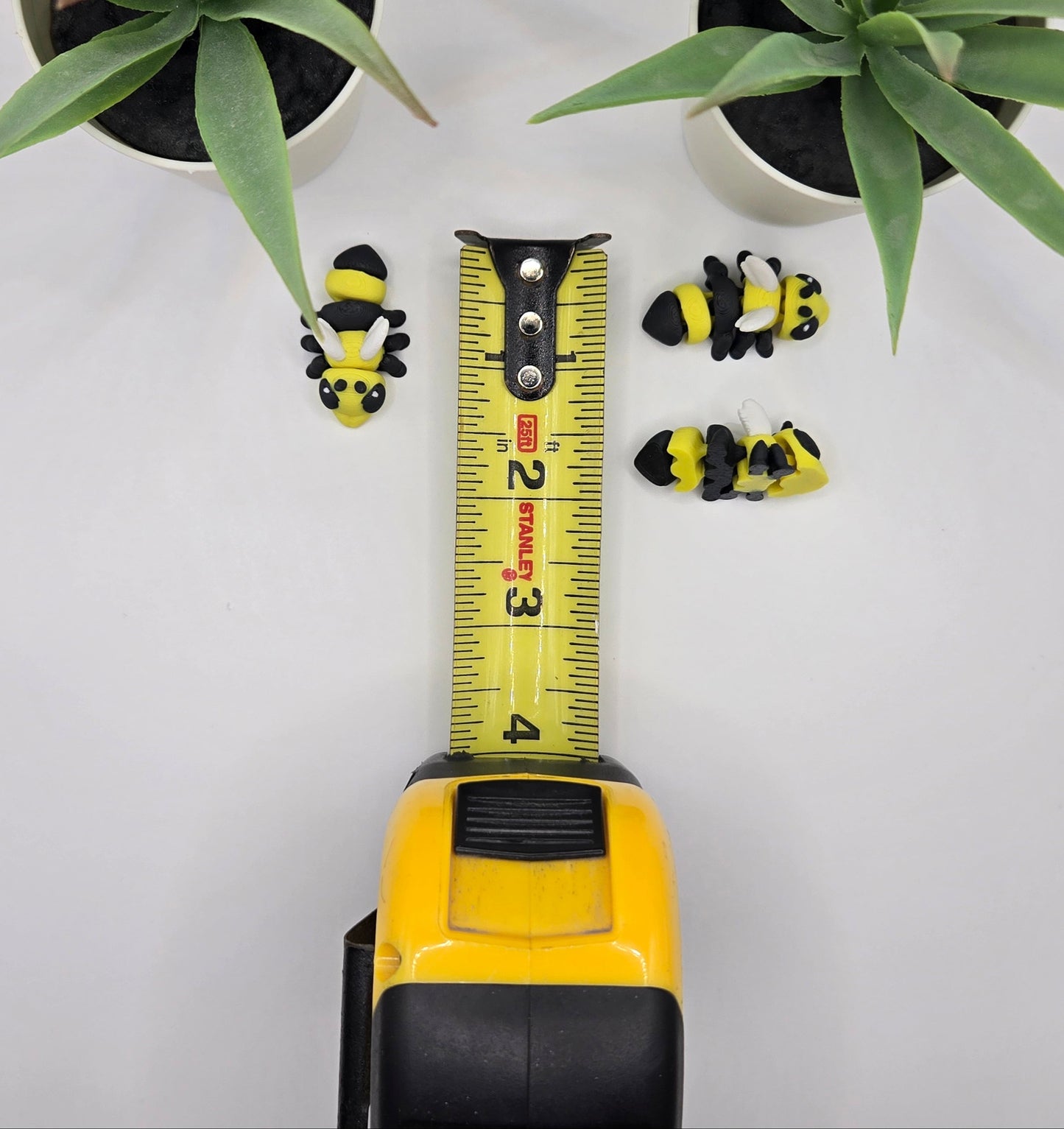 mini articulated hornet toys with a tape measure on a white surface with plants in the background