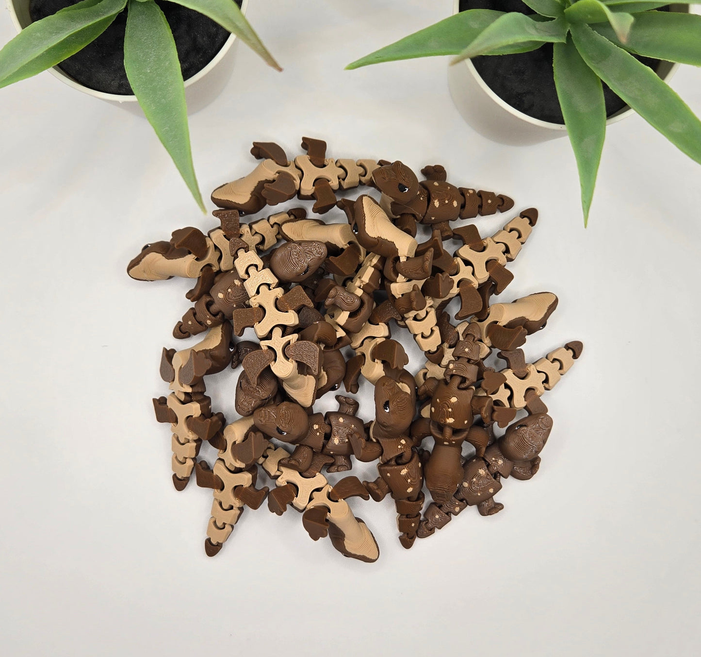 a pile of articulated komodo dragons on a white dragon with plants.