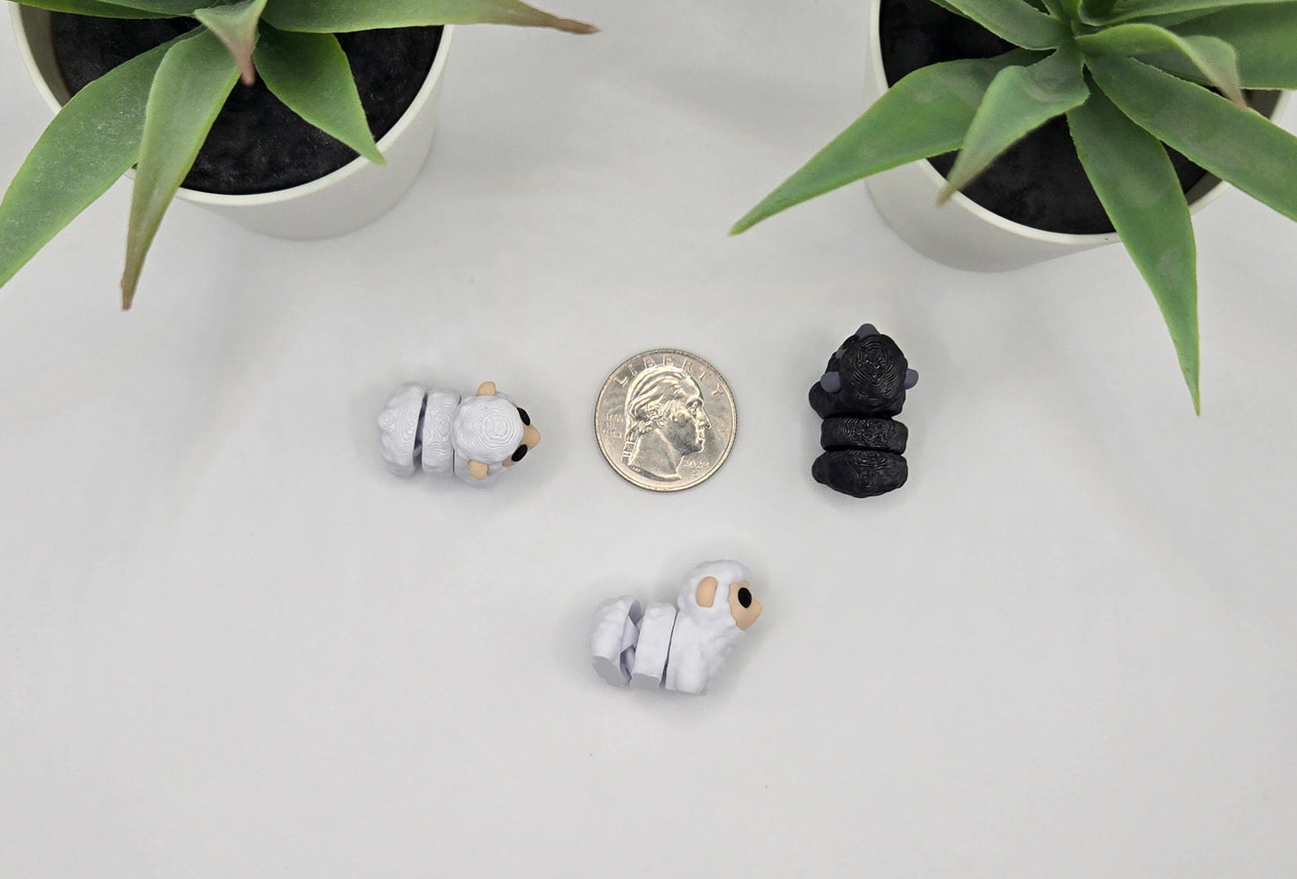 small articulated sheep toys with a quarter on a white surface with plants in the background