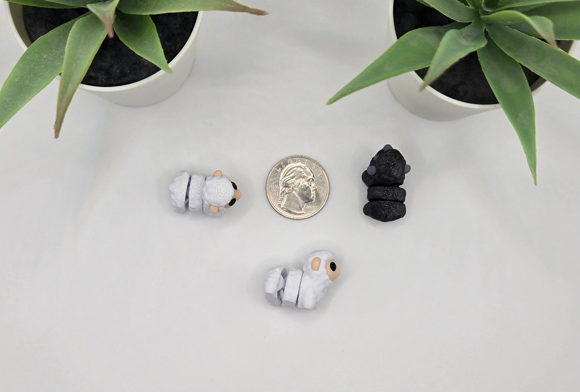 small articulated sheep toys with a quarter on a white surface with plants in the background