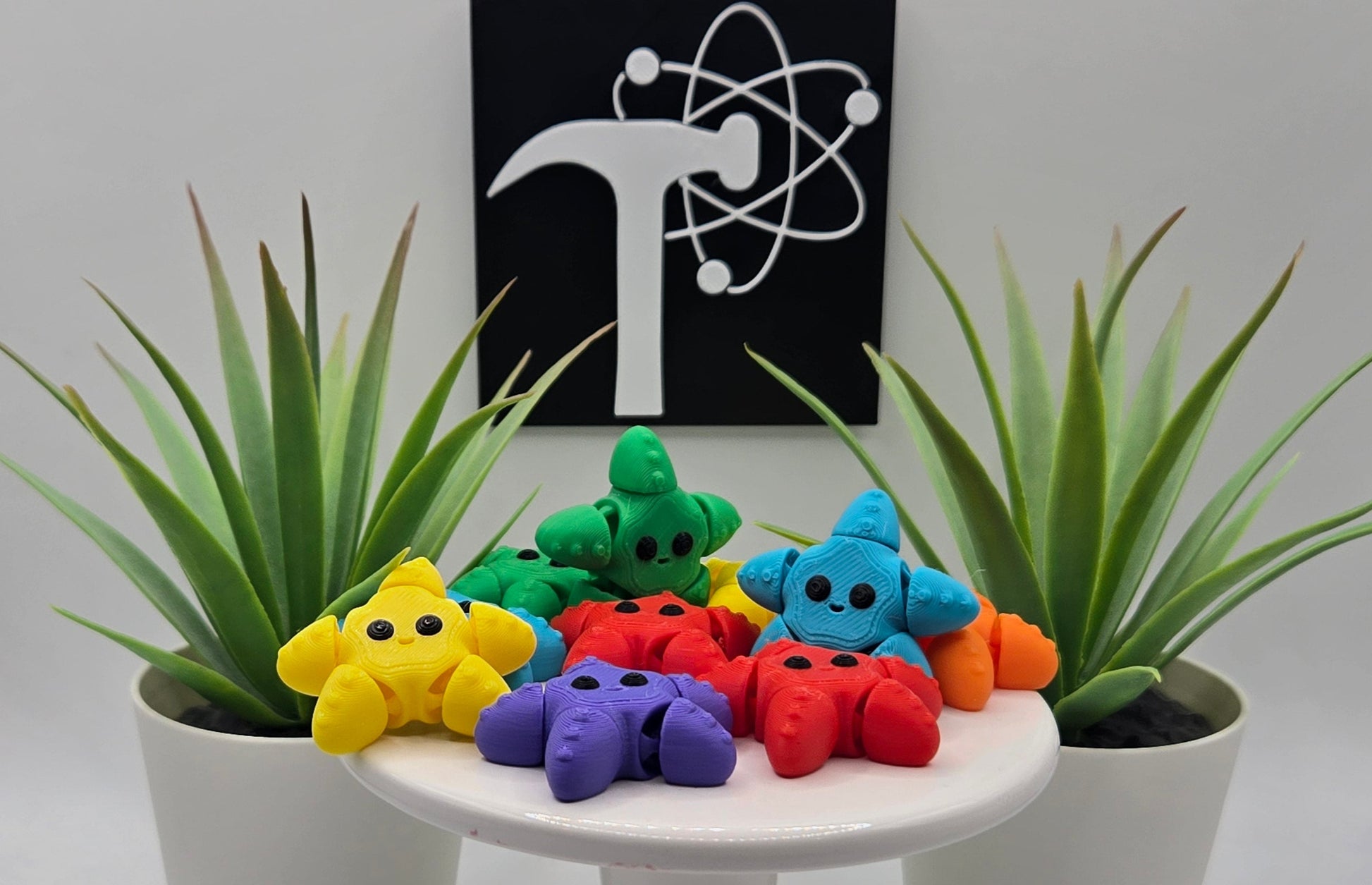 colorful articulated starfish on a white pedestal with two plants and the Crafticist logo in the background.